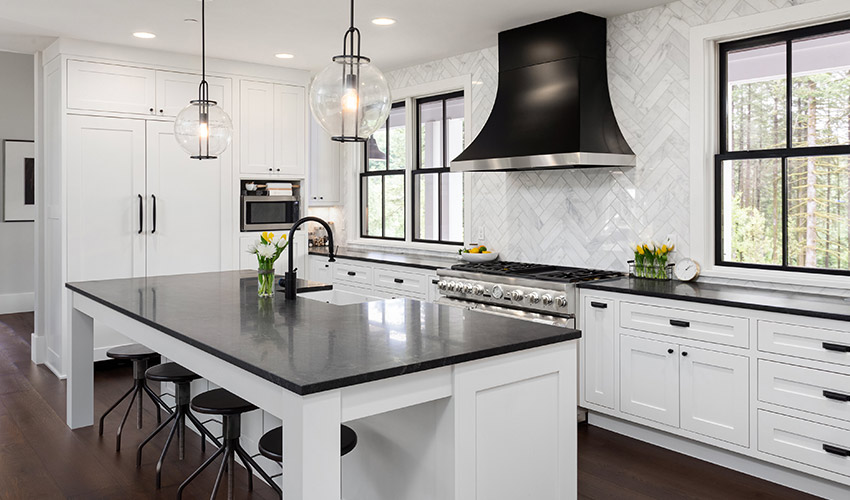 Modern kitchen with bar stools, black countertops, white cabinets, and white tiling