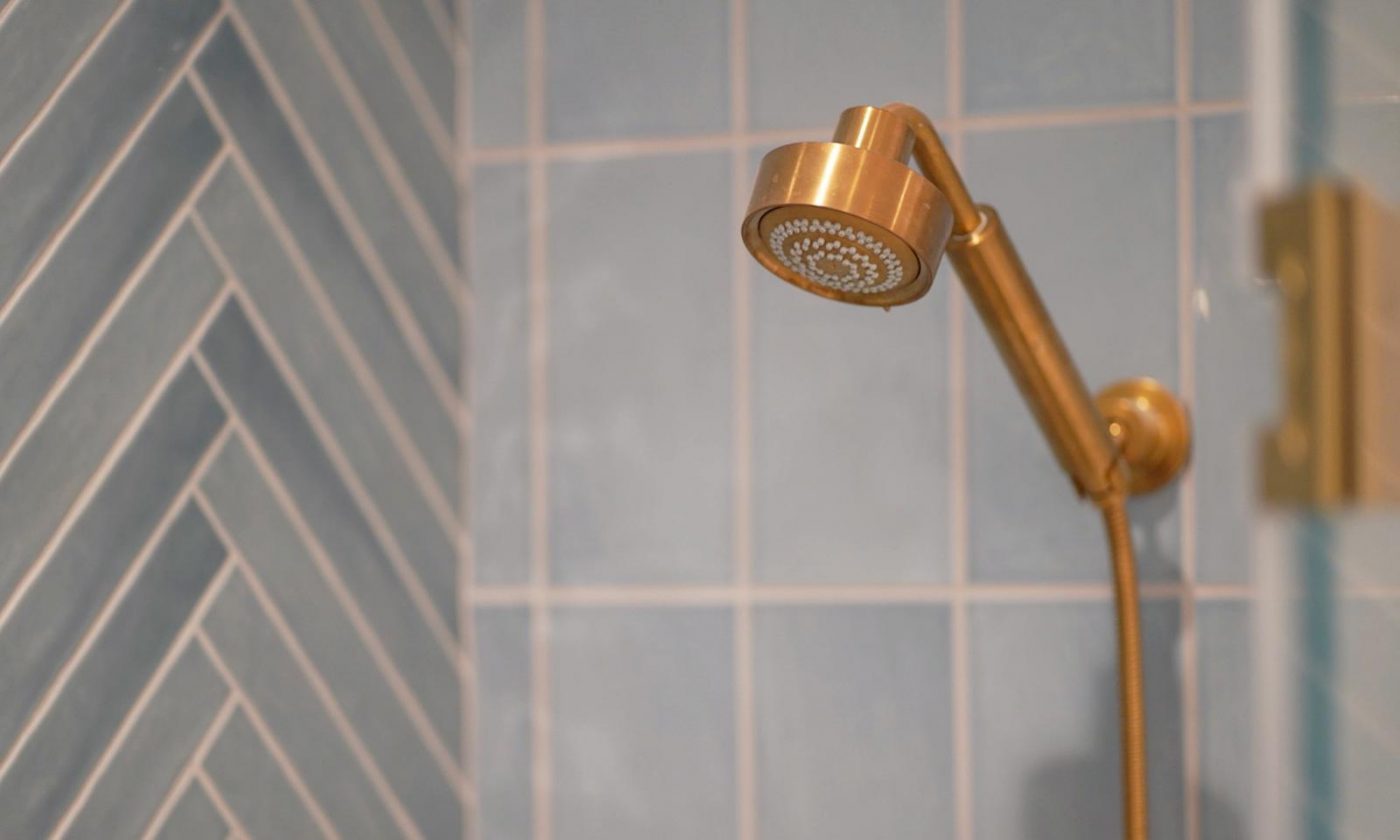 Brass shower head in a blue tiled shower